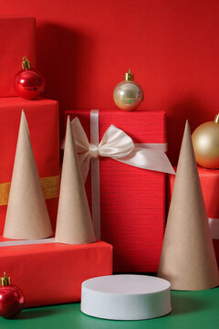 Minimalist Christmas podium mockup with red gifts and tree cones on red background