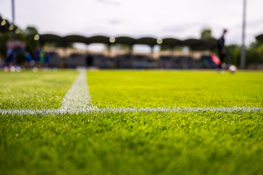 Close-up of soccer field  lines under natural daylight, real sports atmosphere with vivid green turf and stadium background.