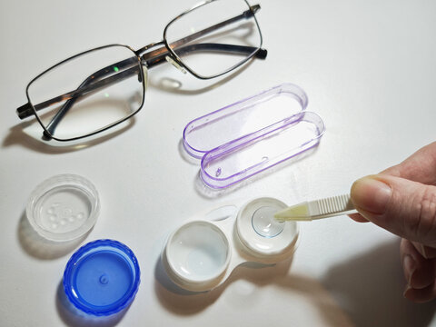 Daily lens care routine with contact lenses, case, solution, and glasses on a clean surface