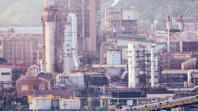Industrial factory plant and steel mill with white smoke emitting from chimney in Muroran, Hokkaido, Japan. Cinematic heavy industry infrastructure background, fixed 4K video.