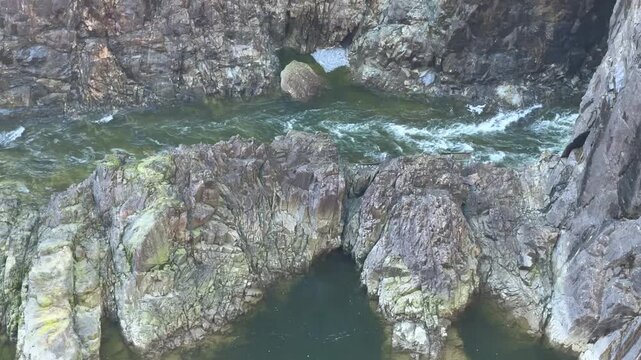 Deep green canyon pool below Cleveland Dam at Capilano River in Vancouver, surrounded by steep rocky cliffs and green forest in a dramatic natural gorge.
