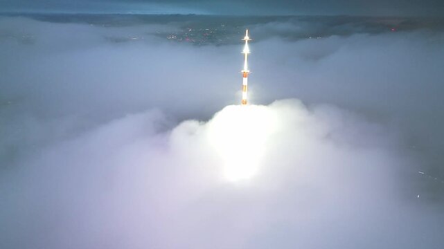 Rocket launching through clouds above city lights at night