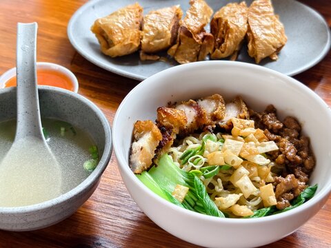 Bakmi topped with crispy pork belly,fried wonton skin crisps, and fried beancurd skin rolls 