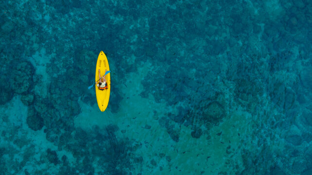 Aerial view of a woman and a young man kayaking on clear blue waters at Andaman Island. She does water sports activities.	
