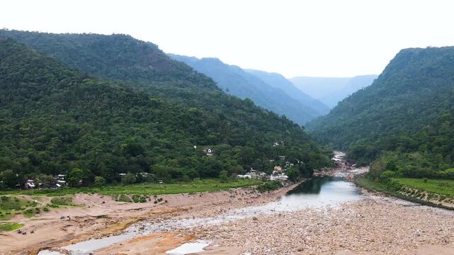 Aerial view of Bichanakandi with a rocky dry riverbed, forested Khasi Hills, scattered indigenous homes and the Bangladesh&ndash;India border landscape near Sylhet.