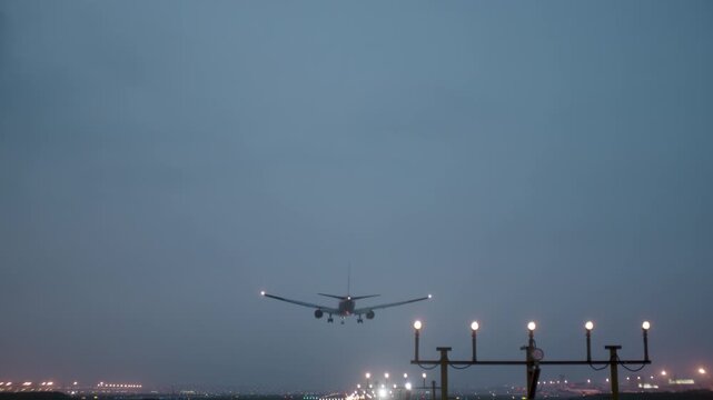 Commercial passenger airplane aircraft landing and braking at foggy, above approach light at airport, approach light system concept. Airport runway approach lights, fence for security