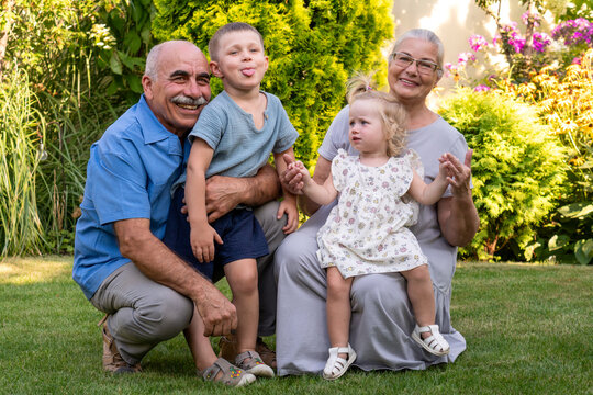 Happy Grandparents Posing With Playful Grandchildren Outdoors