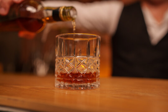 Bartender Pouring Whiskey into Crystal Glass on Bar Counter