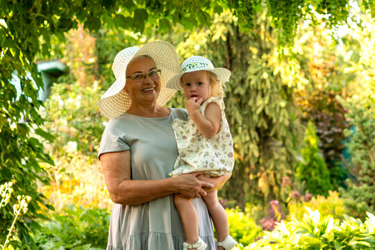 Grandmother Holding Granddaughter In Matching White Summer Hats