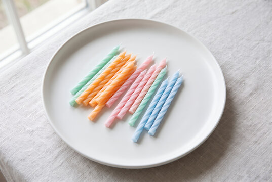 Colorful spiral birthday candles arranged on white ceramic plate