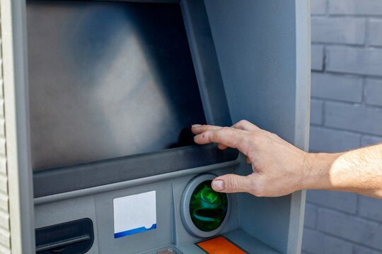 Close up of a man hand using an automated teller machine to enter a pin code or touching the blank screen