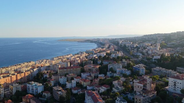 Wide aerial along the Baie des Anges toward the airport runway, hillside villas and apartment blocks in late afternoon sun, Nice, French Riviera, Cote d Azur, France