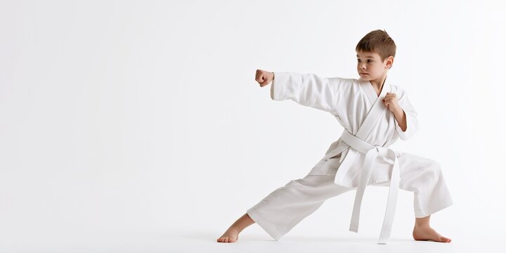 Karate little boy in action isolated on white background, martial arts kick