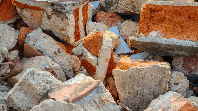 Close-up of a pile of mixed construction waste with broken concrete blocks, red clay brick fragments, and masonry debris at a demolition site.