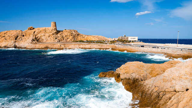 L'Isola Rossa con la torre genovese ed il faro di Pietra si staglia con il suo color ocra intenso nel blu delle acque del Tirreno. Ile Rousse, Corsica, Francia
