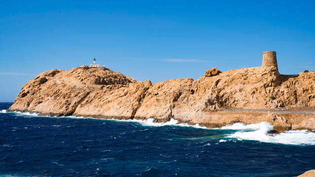 L'Isola Rossa con la torre genovese ed il faro di Pietra si staglia con il suo color ocra intenso nel blu delle acque del Tirreno. Ile Rousse, Corsica, Francia