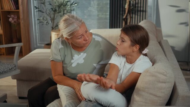 Frustrated girl talks to her grandmother about a personal problem during a tense conversation at home, showing family conflict, misunderstanding and intergenerational communication.