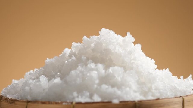 360-degree close-up of a mound of white salt crystals on a natural wooden tray, highlighting the crystalline texture and clean appearance for food and seasoning commercial content.