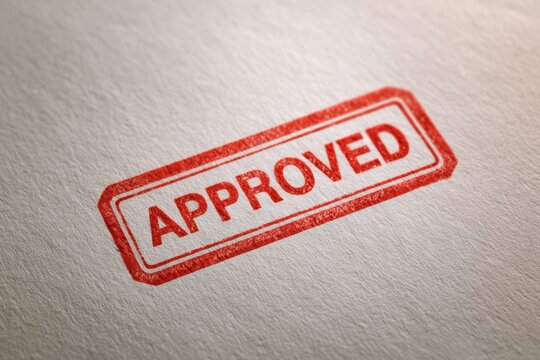 Red approved stamp mark on a textured white paper background