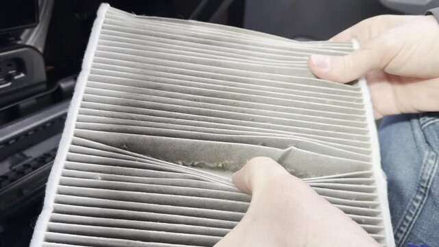 A very dirty car cabin air filter. A man shows the old air filter, close-up.