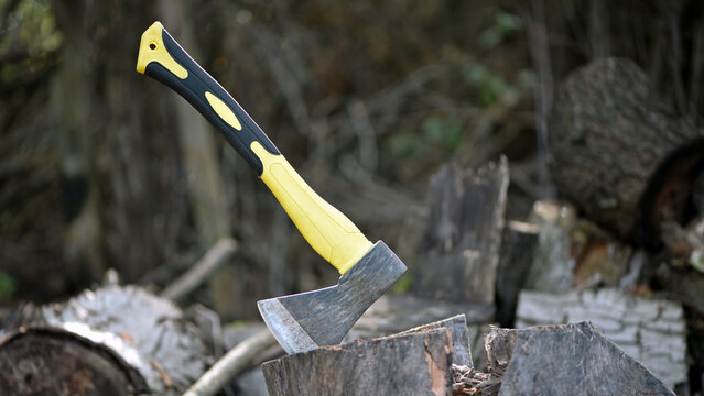an axe in a stump. axe embedded in a wooden log, evoking notions of forestry, craftsmanship, and outdoor activities in nature. preparing firewood for the winter. work in the village. active lifestyle