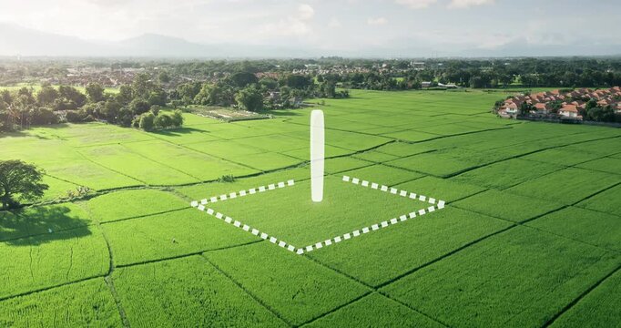 Elevated view of lush green rice fields bordered by trees and homes. Animated white dashed lines outline one land parcel beneath rotating location pin, plot demarcation against sunlit rural scenery.