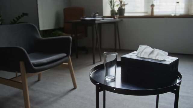 Psychotherapy consultation room prepared with tissue box and drinking glass for patient session. Clip ideal for mental wellbeing campaigns and psychological therapy service promotion