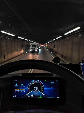 A truck travels through an illuminated tunnel with oncoming traffic ahead, road logistics, driving perspective, transport infrastructure.