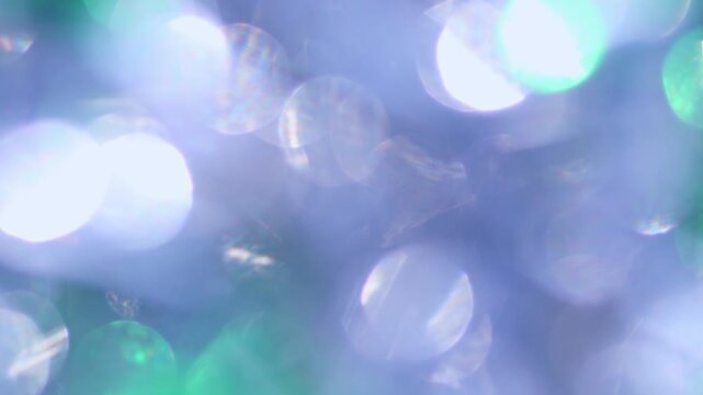 Abstract sparkling green bokeh against blue festive background, rainbow caustic light leaks reflection, glittering holiday celebration for Christmas, party and design.
