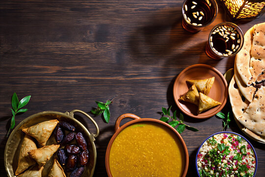 Overhead view of an iftar spread on a dark wooden table