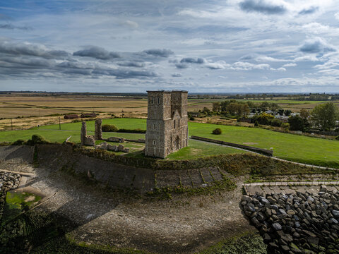 Elevated view of the medieval twin spires of Reculver Towers (The Twin Sisters) and coastal defense wall overlooking green fields in Kent, England