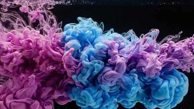 Pink and blue ink plumes billow and blend in liquid against a black background. Abstract fluid motion. Color mixing and pigment diffusion. Artistic texture and dynamic flow.