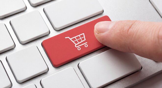 A finger pressing a red computer keyboard key featuring a white shopping cart icon symbol with view human finger e commerce close view communication