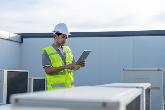 Asian maintenance engineer works on the roof of factory. contractor inspect compressor system and plans installation of air condition systems in construction. technology, online, mobile application.