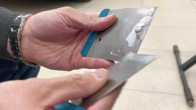 Professional auto mechanic man hands mixing two component polyester car body filler putty with a steel spatula knife tool. Professional vehicle bodywork repair, scratch, dent restoration. 