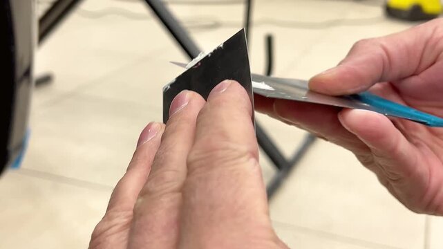 Professional auto mechanic man hands mixing two component polyester car body filler putty with a steel spatula knife tool. Professional vehicle bodywork repair, scratch, dent restoration. 
