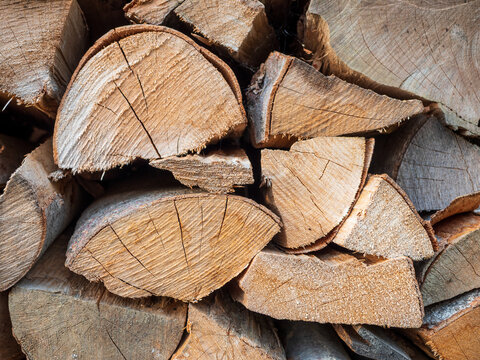 Stacked and stored split beech firewood showing cut ends and natural wood texture. Chopped hardwood prepared and stored as fuel for stove, fireplace and home heating.