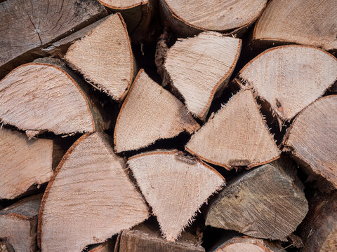 Stacked and stored split beech firewood showing cut ends and natural wood texture. Chopped hardwood prepared and stored as fuel for stove, fireplace and home heating.
