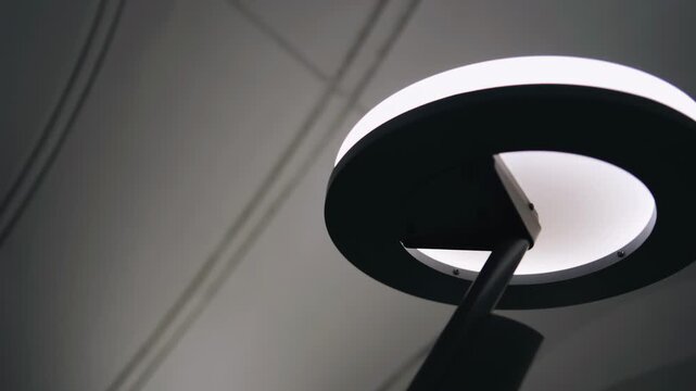 A round light fixture in the subway, filmed while moving up the escalator. Close‑up in motion.