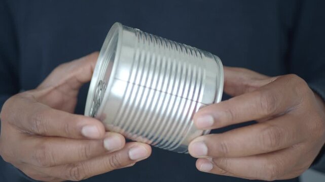 Man holds a can and prepares to open it with his hands