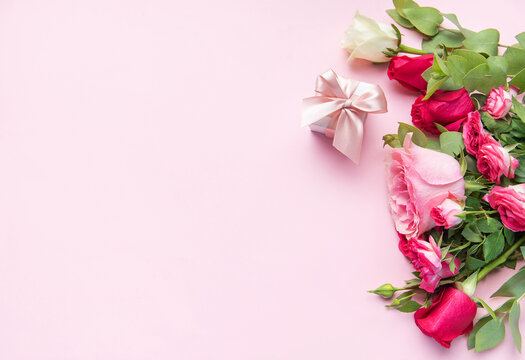 Rose bouquet and gift box on pink background