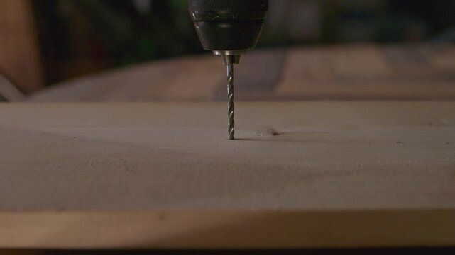 Close-up of a rotating drill bit creating a hole in a wooden board, illustrating woodworking, construction, carpentry and DIY activity.