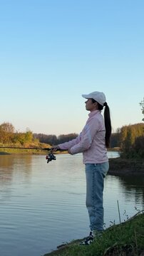 Side view of a woman fishing from the shore on an autumn day