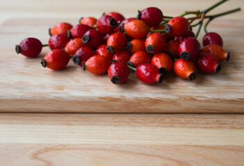 Fototapeta premium Rose hips for herbal medicine and nutrition, fresh red berries on a wooden cutting board for organic skincare and natural vitamin c supplement source