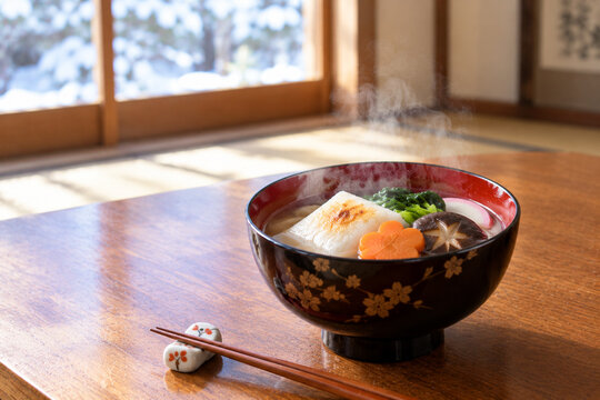 Hot Japanese Ozoni New Year Mochi Soup with Steaming Broth in Traditional Tatami Room with Snow View
