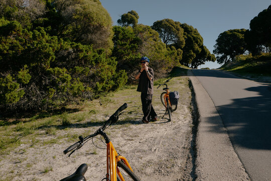 Man unfastening his helmet beside bicycles on a sunny summer roa