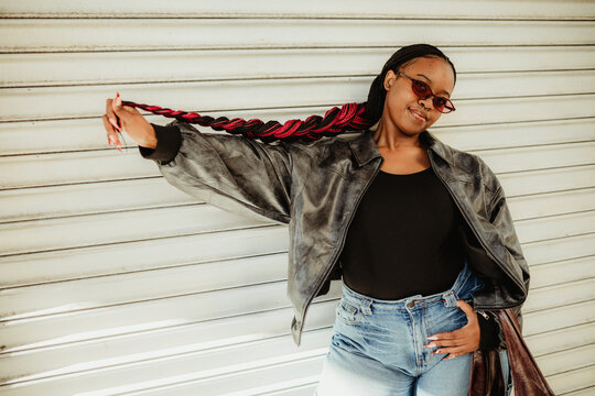 Stylish young Black woman with red braids posing outside