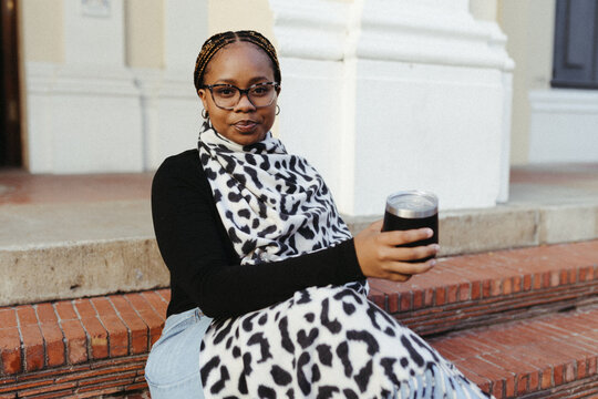 Stylish black woman with glasses sits on brick steps