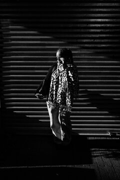 Stylish woman standing in dramatic striped light and shadow