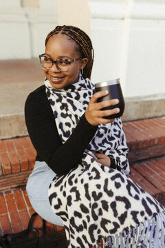 Happy young woman in a scarf sitting outside on steps